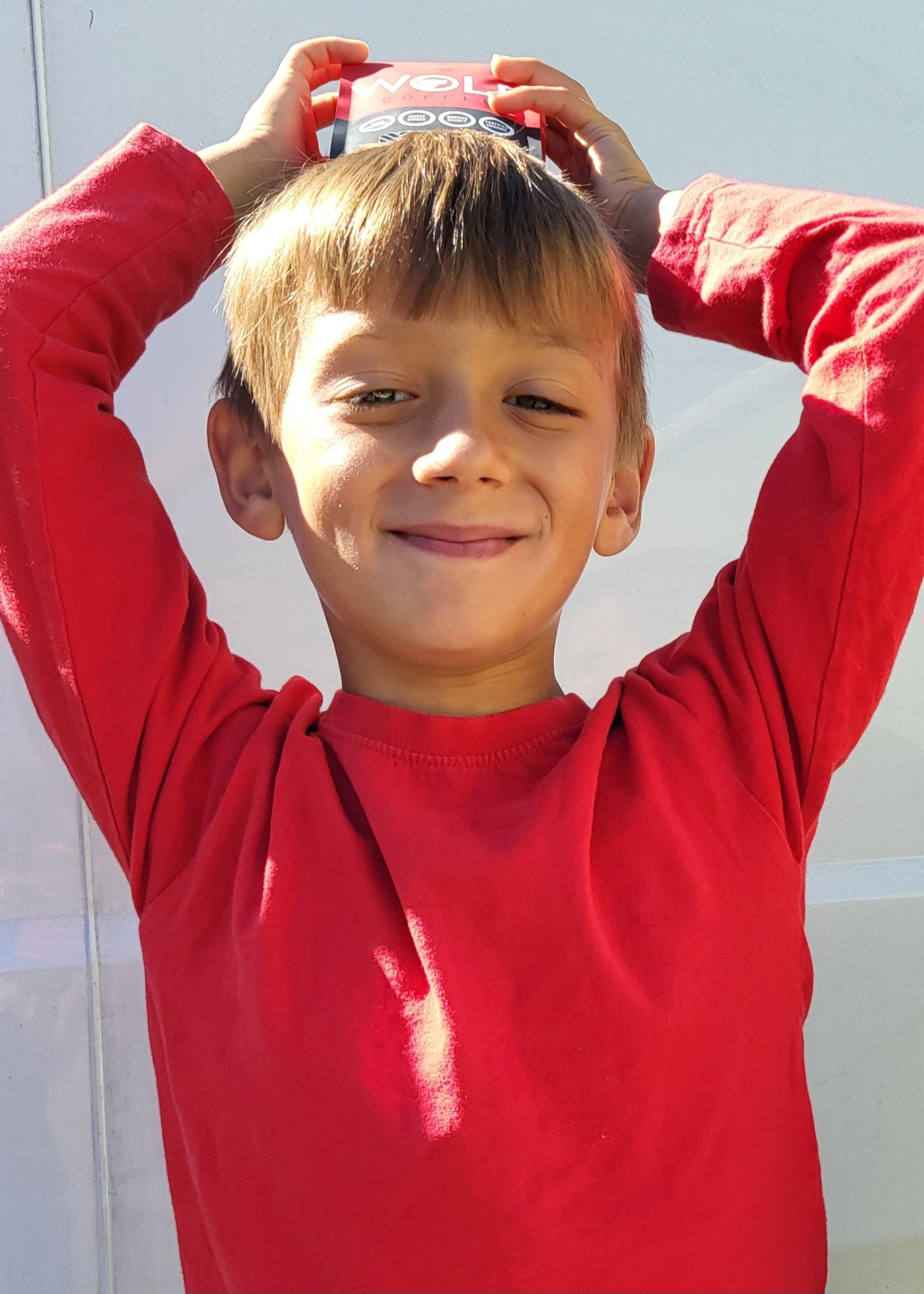 Child wearing a red shirt with a product on their head against a white background
