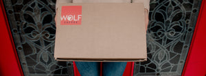 Wolf Coffee delivery package held up by a customer standing in front of door.