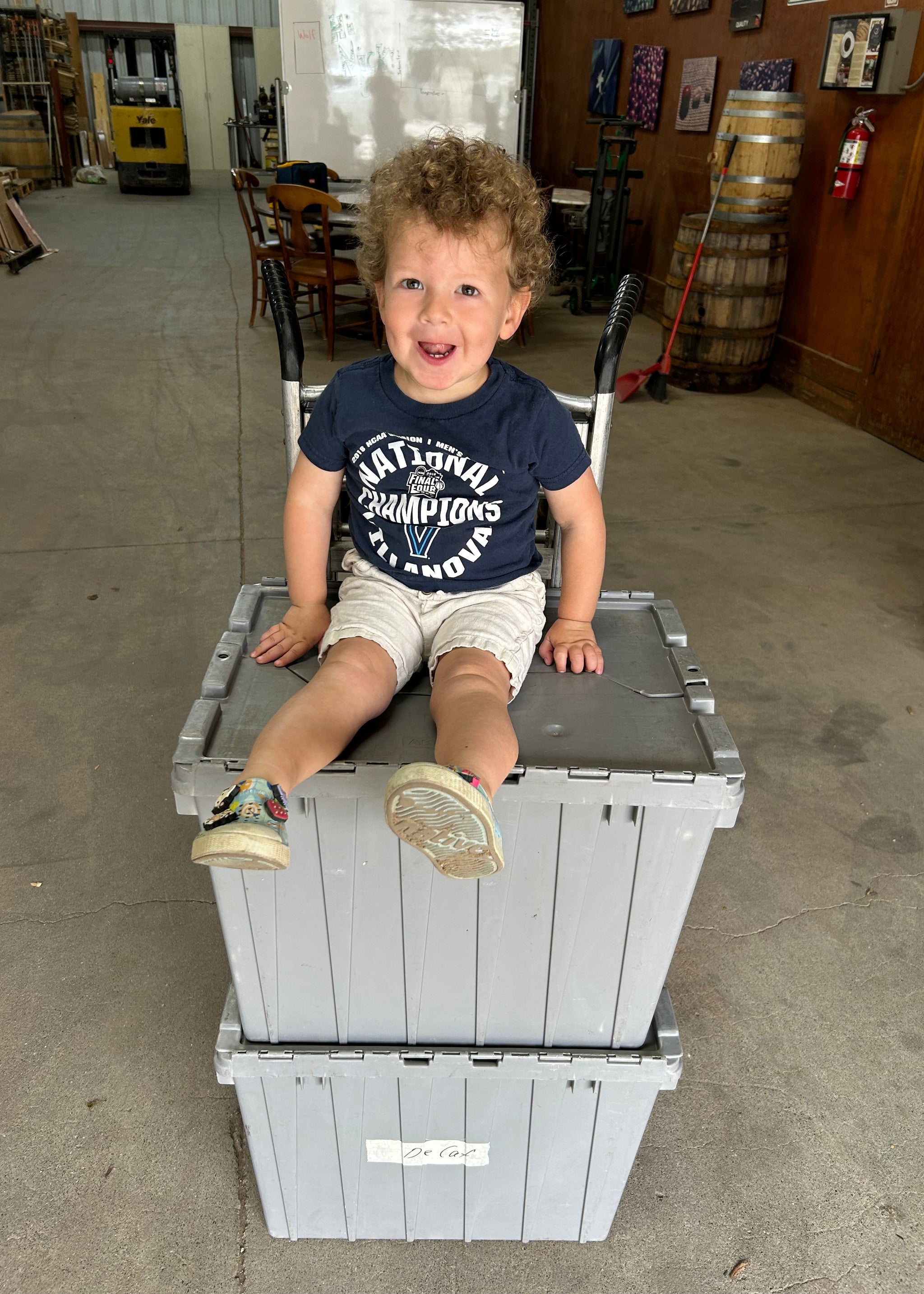 Child sitting on a metal storage crate in an indoor setting